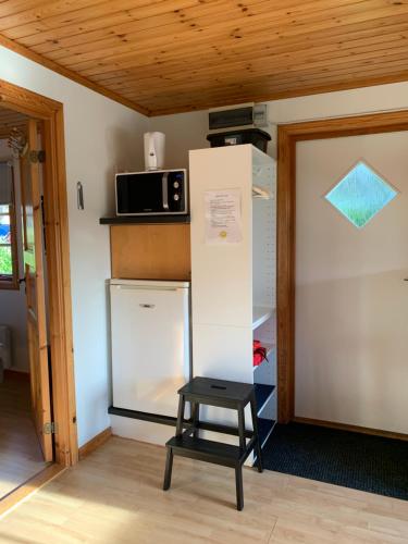 a small kitchen with a refrigerator and a stool at Villa Sus & Dus in Yngsjö