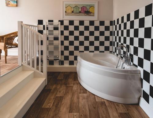 a tub in a bathroom with a checkered wall at Church Farm Winterton-on-sea in Winterton-on-Sea