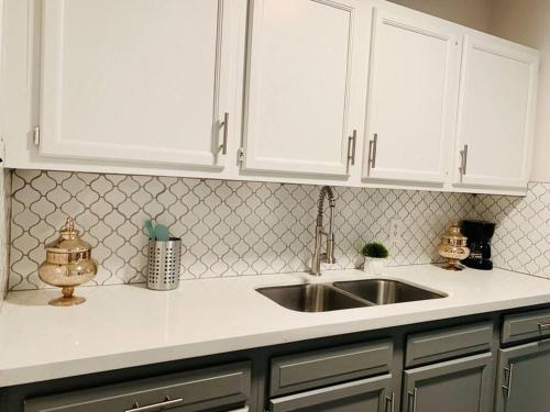 a kitchen counter with a sink and white cabinets at Mayfield @ Oyster Creek - Tranquil Creek & Nature! in Sugar Land
