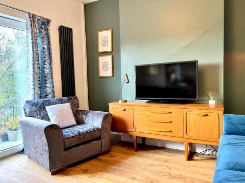 a living room with a television on a wooden dresser at Brecon View by Switchback Stays in Newport