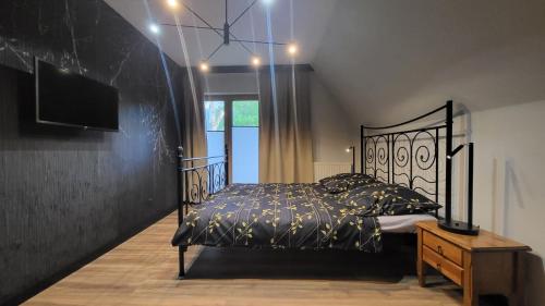 a bedroom with a black bed and a tv at Willa Pod Reglami in Zakopane