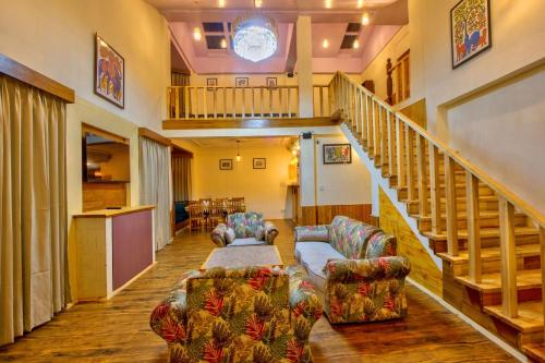 a living room with two couches and a staircase at Baan by Snow City Farm in Vashisht