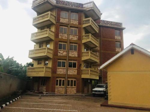 a large brick building with balconies and a parking lot at Jusvero Motel in Jinja