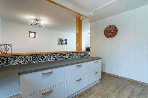 a kitchen with white cabinets and a clock on the wall at Monesto Gite maison de ville cité médiévale in Mennetou-sur-Cher