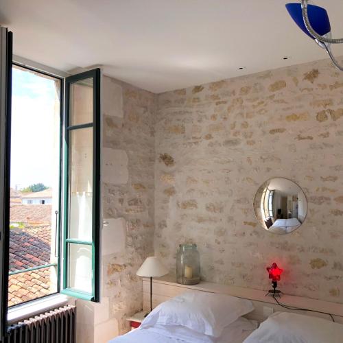 a bedroom with a bed and a mirror and a window at Hôtel Le Sénéchal in Ars-en-Ré