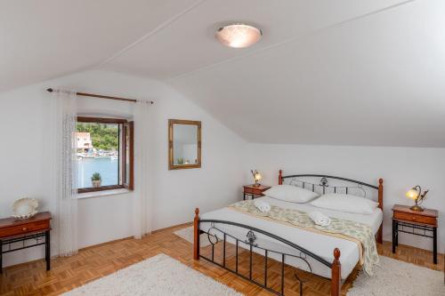 a bedroom with a bed and two tables and a window at Holiday Home By The Sea--Bougainvillea in Ston