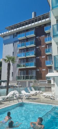two people in a swimming pool in front of a building at Appartamenti Katja in Bibione