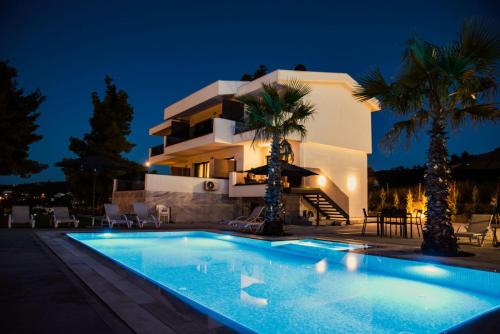 a villa with a swimming pool at night at Pine Resort in Polychrono