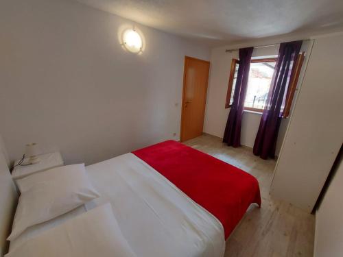 a bedroom with a white bed with a red blanket at Sweet Sea Apartments in Pakoštane