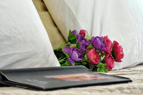 a laptop on a bed next to a bouquet of flowers at Espianade Studio in Corfu Town