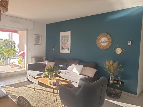 un salon avec un canapé et un mur bleu dans l'établissement Appartement calme avec jardin Bidart Biarritz, à Bidart