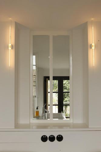 a mirror above a sink in a bathroom at Hôtel Le Sénéchal in Ars-en-Ré