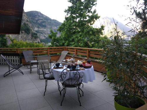 a table and chairs on a patio with mountains in the background at La Marmotte de la Tour in Hermillon