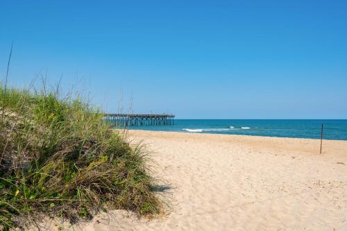 a sandy beach with a pier in the ocean at Siers Seashore in Waves
