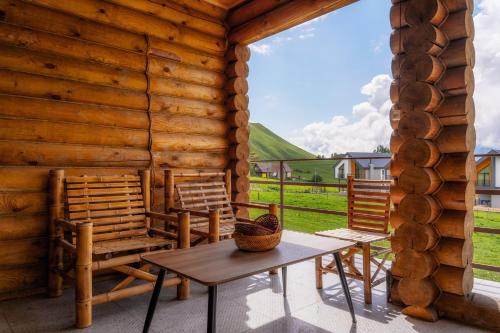 eine Veranda eines Blockhauses mit Stühlen und einem Tisch in der Unterkunft Snow Time Eco Chalet in Gudauri