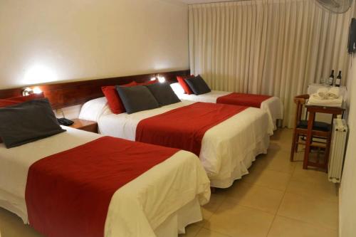 Habitación de hotel con 2 camas con sábanas rojas y blancas en Intersur Villa Gesell en Villa Gesell
