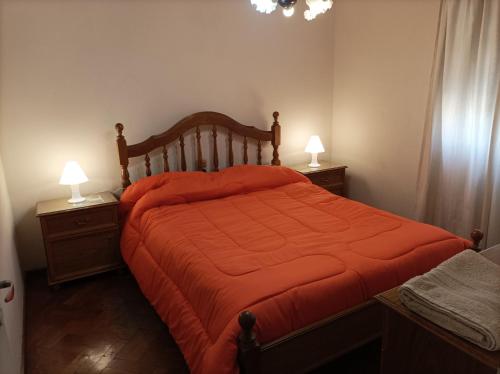 a bedroom with a bed with an orange comforter at Hermoso departamento en Mendoza in Mendoza