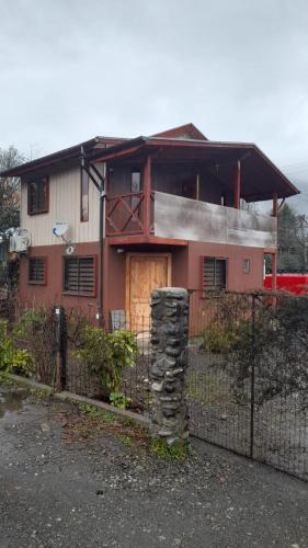 une maison avec une clôture devant elle dans l'établissement Cabaña Punto Punahue, à Choshuenco