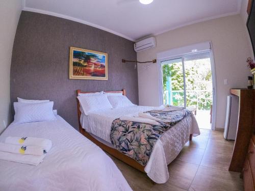 a bedroom with two beds and a window at Residencial Águas de Bare in São Sebastião