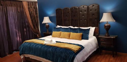 1 dormitorio con 1 cama grande y paredes azules en Lamon Guesthouse, en Kroonstad