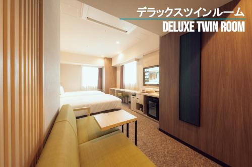 um quarto de hotel com uma cama, um sofá e uma televisão em Henn na Hotel Sendai Kokubuncho em Sendai