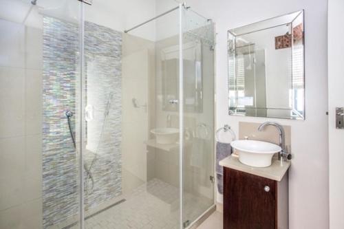 a bathroom with a glass shower and a sink at Sunset Beach holiday accommodation in Cape Town