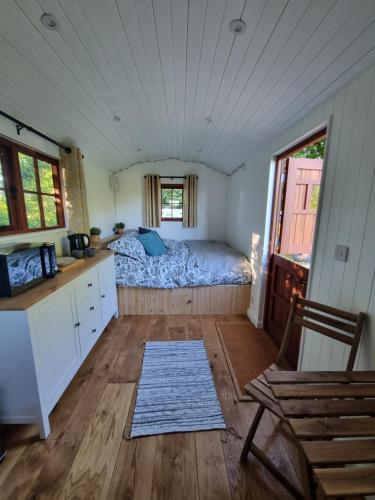 um quarto com uma cama no meio de um quarto em Shepherds hut surrounded by fields and the Jurassic coast em Bridport