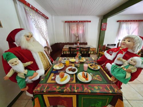 um grupo de Papai Noel em pé em torno de uma mesa com comida em Pousada Natal Encantado em Gramado