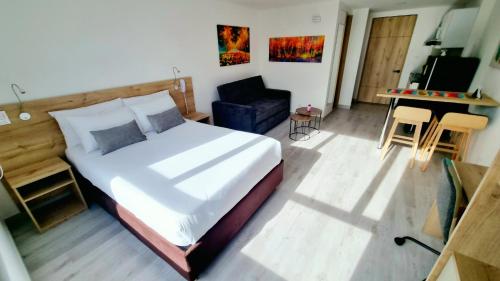 a bedroom with a large bed and a chair at Toscana LOFT - Apartasuites in Bogotá