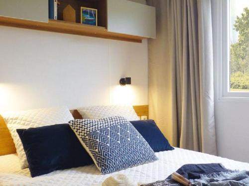 a bedroom with a bed with blue and white pillows at Chalet op Camping Lauwersoog met 3 slaapkamers en vaatwasser - JoyCasa in Lauwersoog