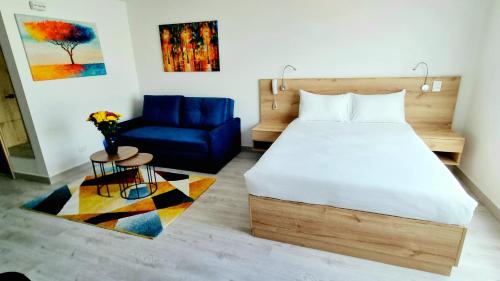 a bedroom with a bed and a blue couch at Toscana LOFT - Apartasuites in Bogotá
