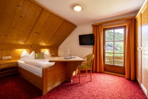 a hotel room with a bed and a desk and a window at Pension Antonia in Fuschl am See