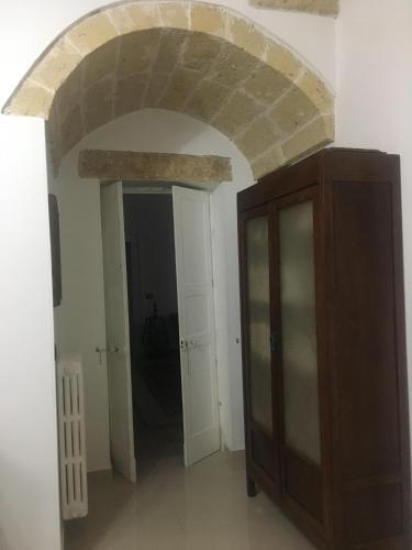 a room with a stone archway and a wooden cabinet at Stelmalu' in Novoli