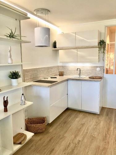 une cuisine blanche avec des armoires blanches et un évier dans l'établissement Charme & Calme-TAMARIS- Studio Vue mer - Piscine - Le Petit Olivier sur Mer, à La Seyne-sur-Mer