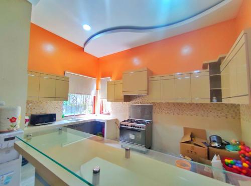 a large kitchen with orange walls and white cabinets at Homestay Parikesit Rent Full House in Semarang