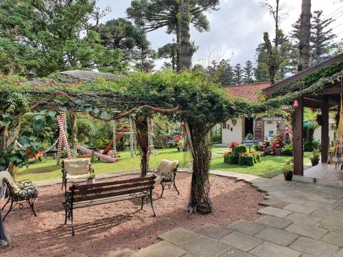 un parque con un banco, un árbol y un parque infantil en Pousada Natal Encantado en Gramado