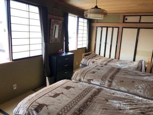 two beds in a room with windows in a bedroom at Guest House Nusa - Vacation STAY 12652 in Kushiro
