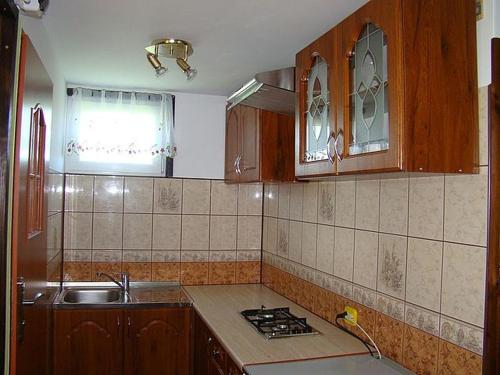 a kitchen with a sink and a stove and cabinets at Domek Letniskowy 7 in Zawóz