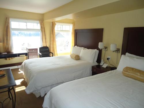 a hotel room with two beds and two windows at Bayside Inn & Waterfront Suites in Kingston