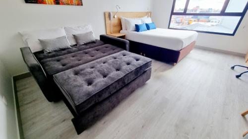 a bedroom with a bed and a tufted couch at Toscana LOFT - Apartasuites in Bogotá