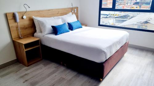 a bedroom with a large bed with blue pillows at Toscana LOFT - Apartasuites in Bogotá