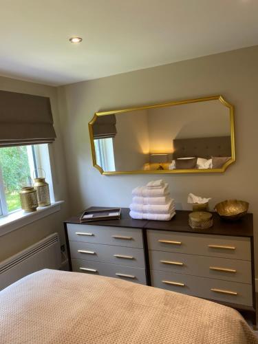 a bedroom with a mirror and a dresser with towels at Gleneagles Holiday Home in Auchterarder