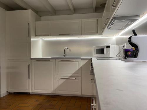 eine weiße Küche mit einer Spüle und einer Mikrowelle in der Unterkunft Capbreton Villa Patio 27m2 5 pers près port plages in Capbreton