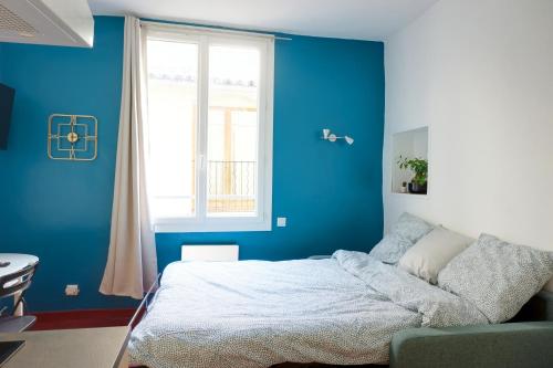 a blue bedroom with a bed and a window at Studio au cœur du village provençale de Riez. Dans le Verdon. in Riez