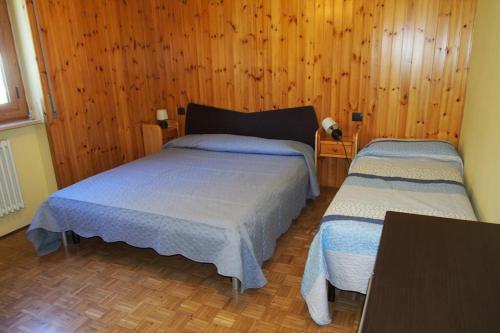 a bedroom with two beds and a wooden wall at Casa vacanza Roberto R2 in Antey-Saint-André
