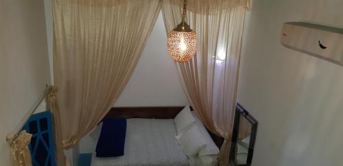 a small room with a bed with curtains and a chandelier at Riad Nerja in Chefchaouene