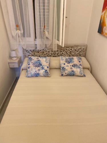 a bed with blue and white pillows and a window at Aqualife luxury home 4 in Arzachena