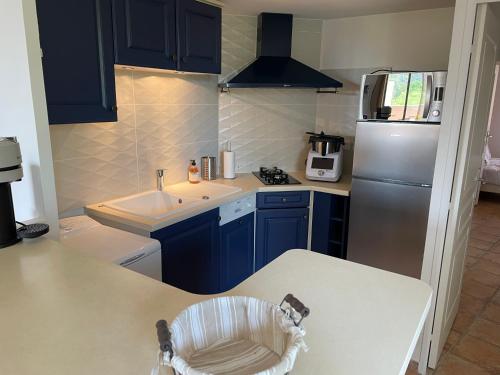uma cozinha com armários azuis, um lavatório e um frigorífico em Superbe appartement au cœur du Luberon. em Goult