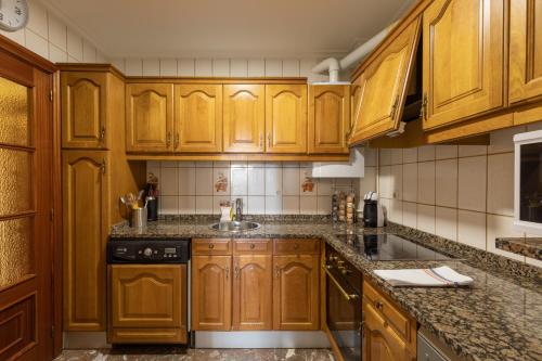 a kitchen with wooden cabinets and a sink at Plaza berri - baskeyrentals in Azpeitia
