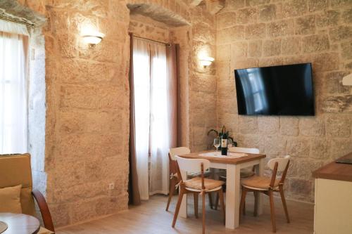 a dining room with a table and a tv on a wall at Sessa's Palace in Korčula